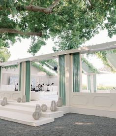 an outdoor wedding venue with green curtains and white steps leading up to the ceremony room