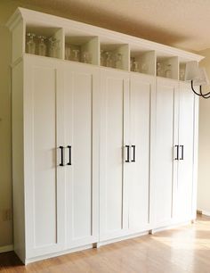 an empty room with white cabinets and wood floors