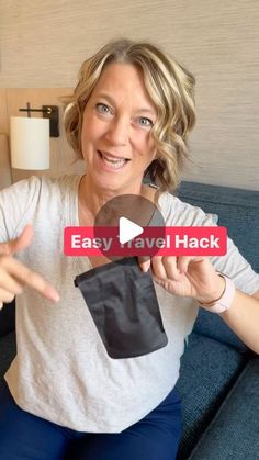 a woman sitting on a couch holding an easy travel hack sticker in front of her face