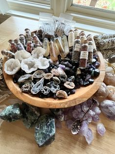 a wooden bowl filled with lots of different types of rocks and stones on top of a table