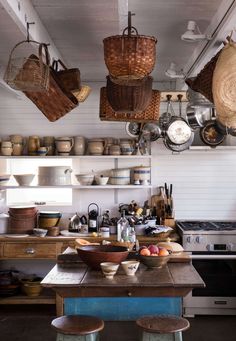 a kitchen filled with lots of pots and pans hanging from the ceiling over an island