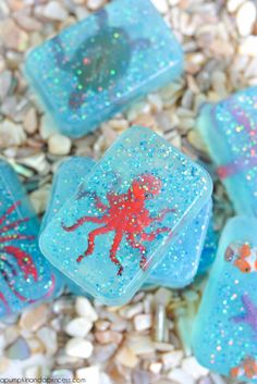 some blue and red soaps with sea animals on them sitting in the sand next to rocks