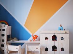 a child's room with colorful wallpaper and toys on the table in front of it