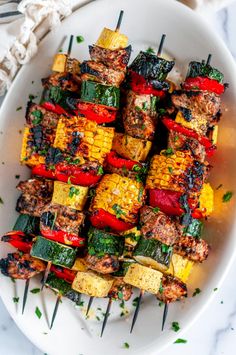 a white plate topped with grilled vegetables on skewers