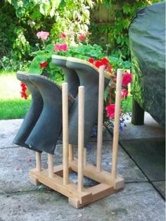 four boots are stacked on top of each other in front of a flower pot with flowers growing out of it