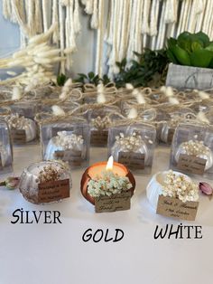 there are many small candles on the table with tags in front of them that say silver, gold, and white