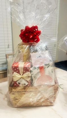 a basket filled with lots of wrapped presents on top of a table next to a window