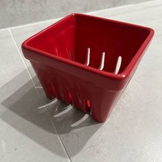 a red container with toothbrushes in it sitting on the ground next to a tile floor