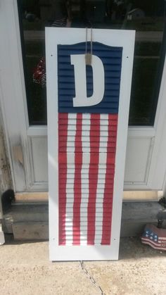 a door sign with the letter d painted in red, white and blue on it