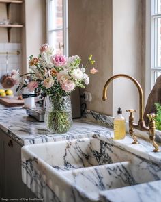 a vase filled with flowers sitting on top of a kitchen counter next to a sink