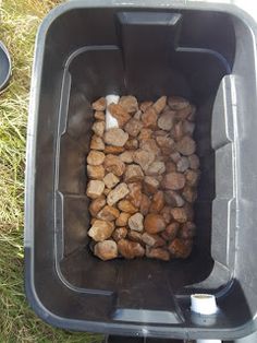 a black trash can filled with rocks on the grass