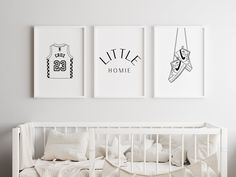 three prints hang on the wall above a crib in a white room with pillows and blankets