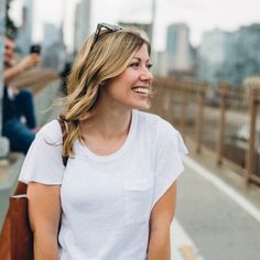 a woman is walking down the street with her hand in her pocket and she is smiling