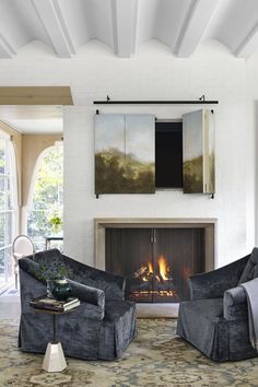 a living room with two chairs and a fire place in the middle of the room