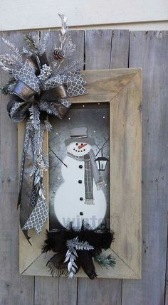 a wooden frame with a snowman on it and a bow hanging from the side