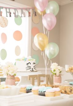 a table topped with cupcakes and cake next to balloons