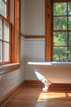 a white bath tub sitting on top of a hard wood floor next to two windows