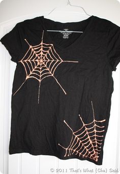 a black t - shirt with spider webs on it