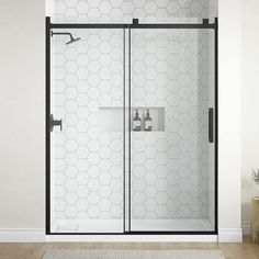 a bathroom with a glass shower door and white rugs on the wooden flooring