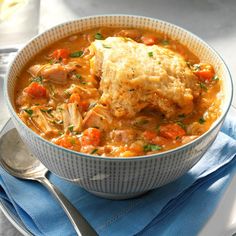 a bowl of chicken and vegetable soup on a blue napkin