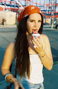 a young woman is eating an ice cream cone in front of some roller coasters