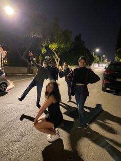 a group of people standing on the side of a road at night with their arms in the air