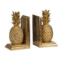 two gold pineapple bookends sitting next to each other