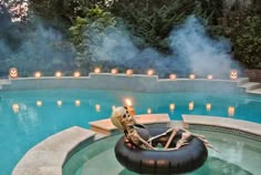 a skeleton sitting in an inflatable chair next to a pool filled with candles