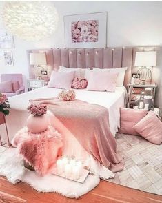 a pink bedroom with candles and flowers on the bed