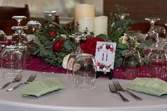 the table is set with wine glasses, silverware and candles for an elegant centerpiece