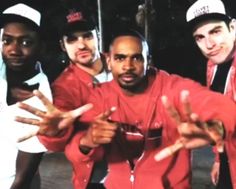 three men in red shirts and white caps posing for the camera with their hands up