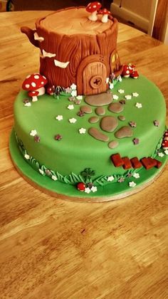 a birthday cake with a tree stump and mushrooms on the top is sitting on a wooden table