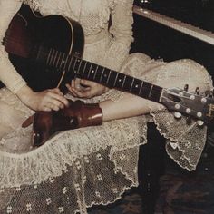 a woman sitting in front of a piano holding a guitar and playing the ukulele