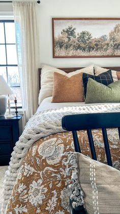 a bed sitting in a bedroom next to a window filled with pillows and blankets on top of it