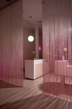 a room with pink curtains hanging from the ceiling and a white counter in front of it