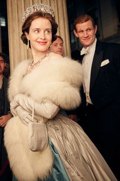 a woman wearing a tiara standing next to a man in a tuxedo