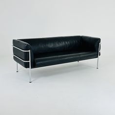 a black leather couch sitting on top of a white floor next to a metal frame