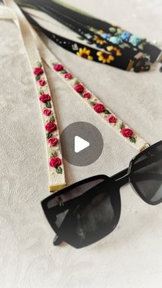 two pairs of black sunglasses sitting on top of a white cloth covered table next to an eyeglass case