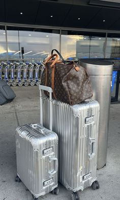 two pieces of luggage sitting next to each other in front of a metal trash can