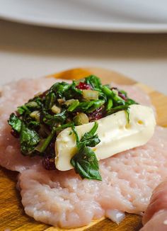 raw fish with spinach and cheese on a wooden board next to other food items