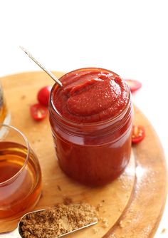 a jar of ketchup sitting on top of a cutting board next to a spoon