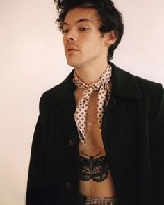 a man with no shirt wearing a black coat and polka dot print neck tie on