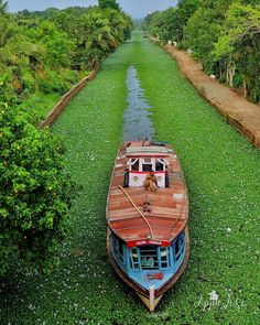 a boat is parked on the side of a narrow waterway in an area with green grass and trees