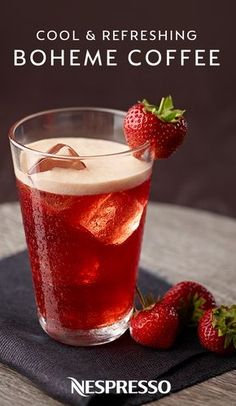 a glass filled with ice and strawberries on top of a table