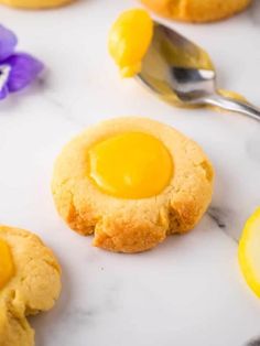 a cookie with an egg in the middle on a marble surface next to purple pansies