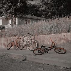 three bikes parked next to each other on the side of a road in front of a house