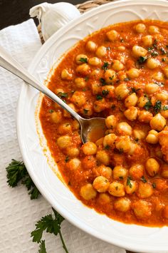 a white bowl filled with chickpeas and garnished in sauce on top of a table