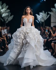 a model walks down the runway in a white gown with ruffles on it