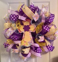 a purple and yellow mesh wreath with a cross on the front door, decorated with polka dots