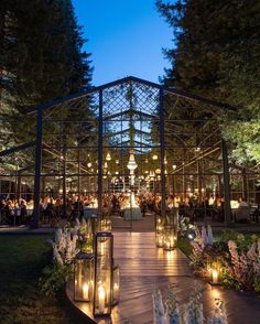 an outdoor wedding venue lit up at night with candles on the walkway and flowers in the foreground